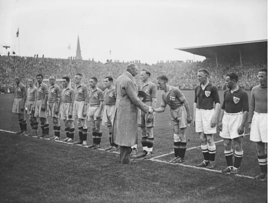 Historic football teams lined up and greeting an official before a match, showing early football history