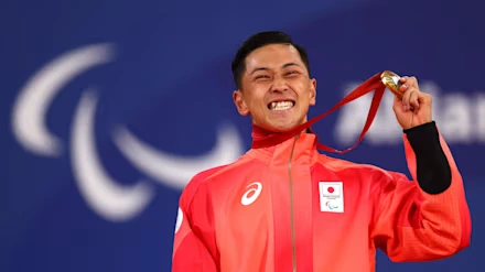 A Japanese Paralympic athlete smiling and holding a gold medal during the Paralympic Games.